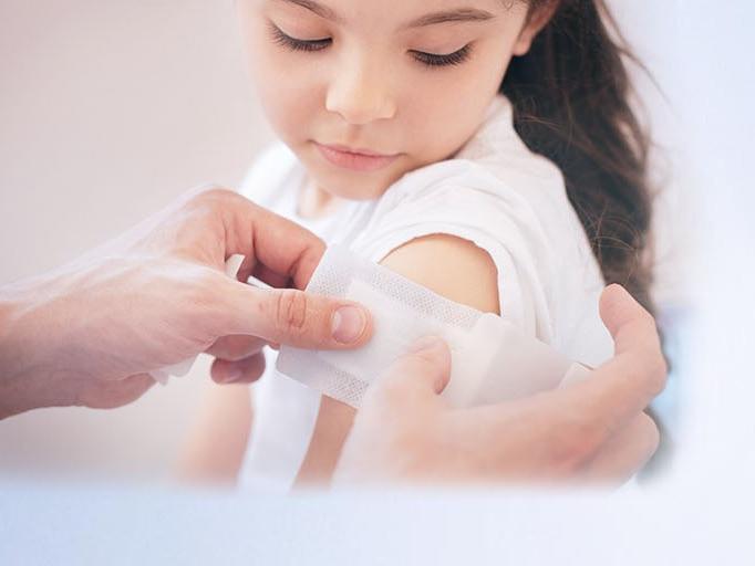 young girl getting a band aid on her arm